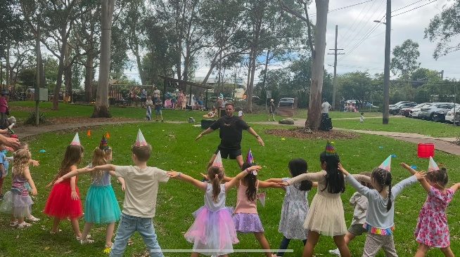 Children in party hats holding hands in a big circle at a birthday party
